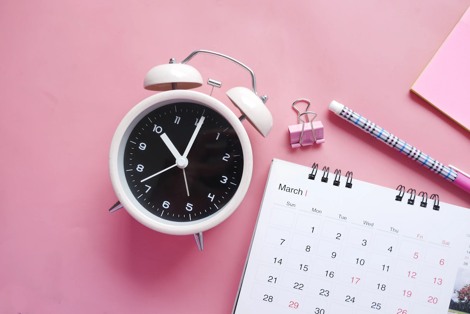 An alarm clock beside a monthly calendar