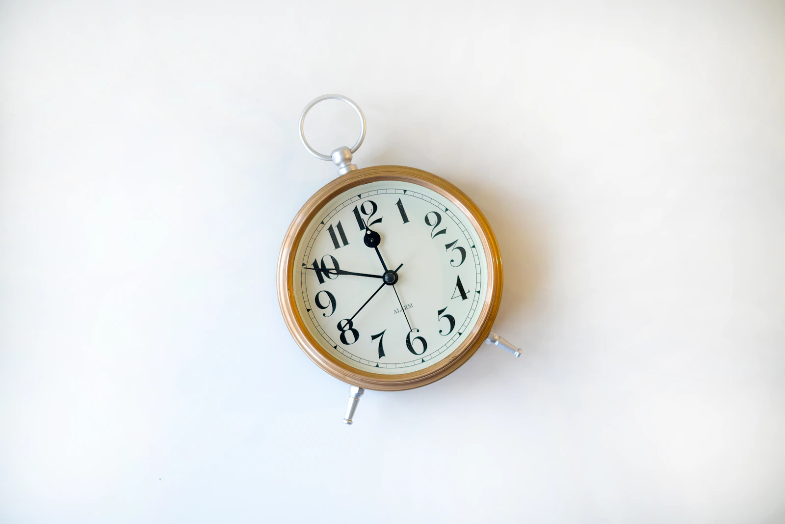 A minimal alarm clock against a clean white wall