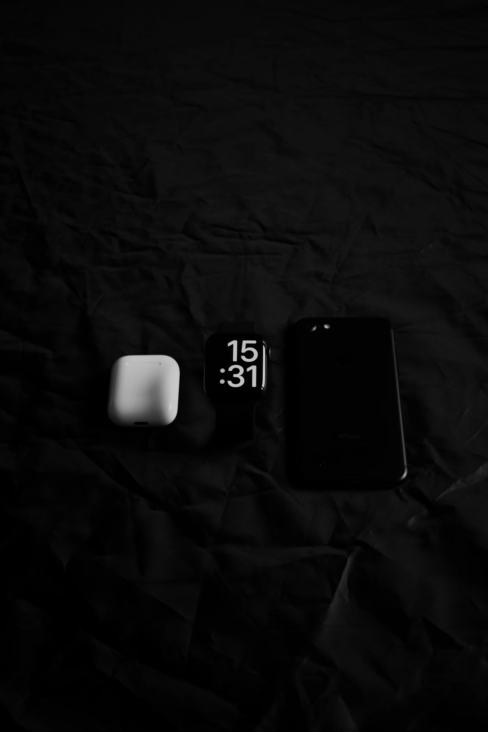 An iPhone and watch resting on a bed