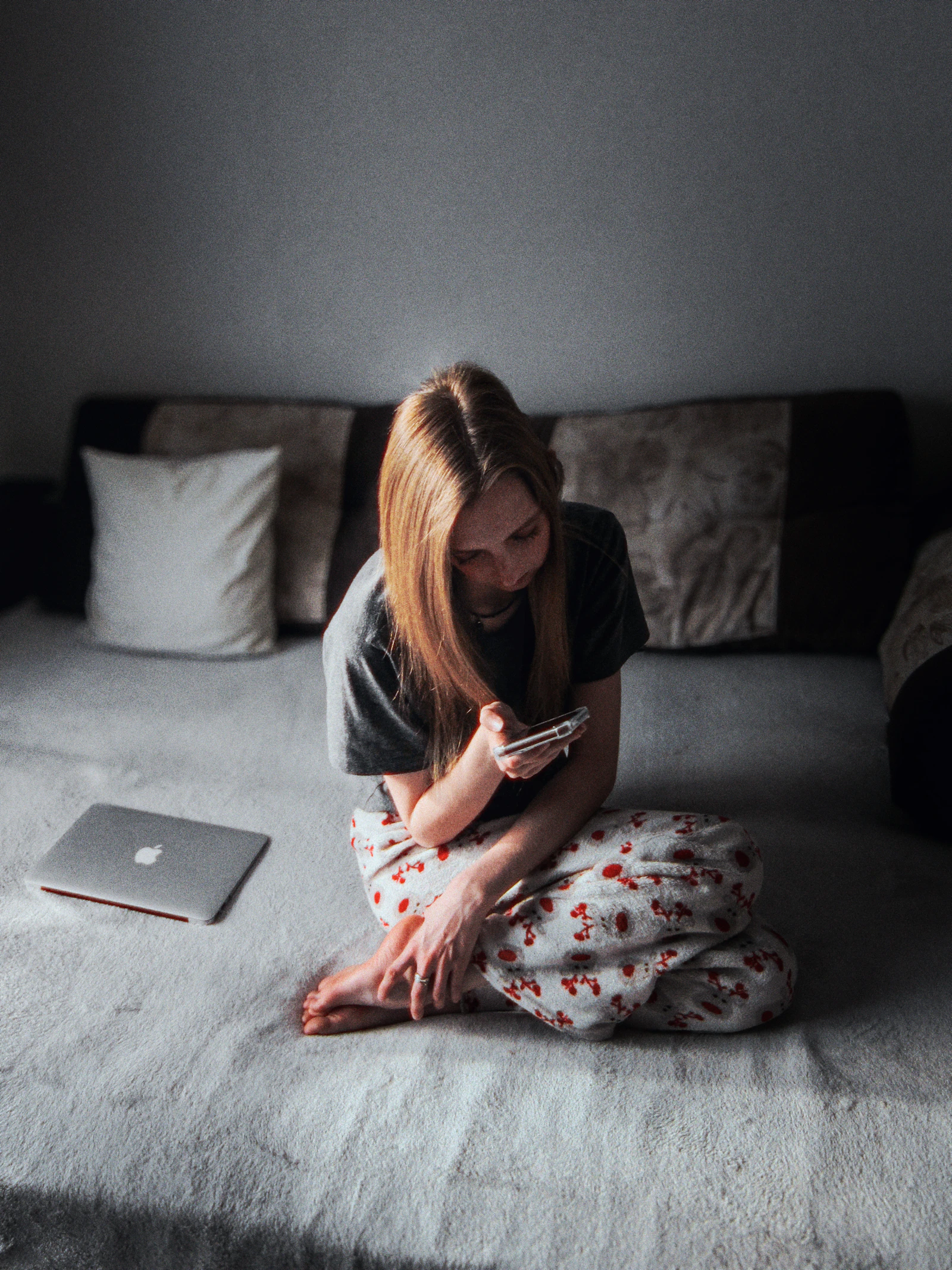 A woman checking her phone while sitting on her bed